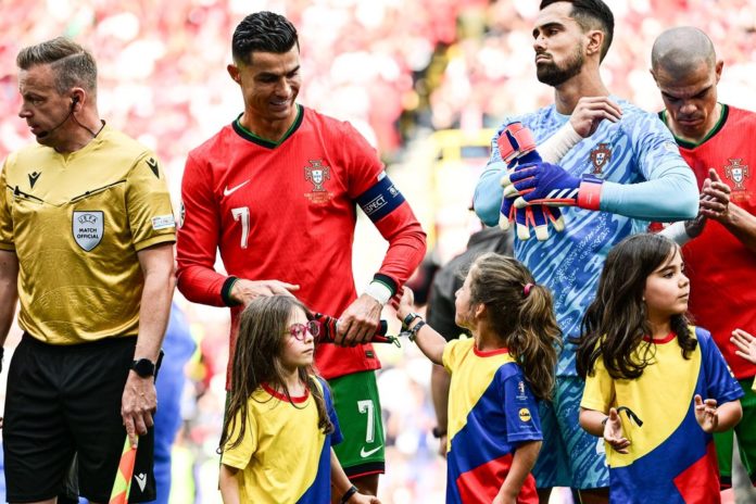 Fußball-EM 2024: Fußball-Superstar Cristiano Ronaldo wird von dem kleinen Einlaufmädchen am Arm berührt. / Source: IMAGO/kolbert-press